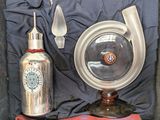a silver object with a red handle next to a bottle and spoon