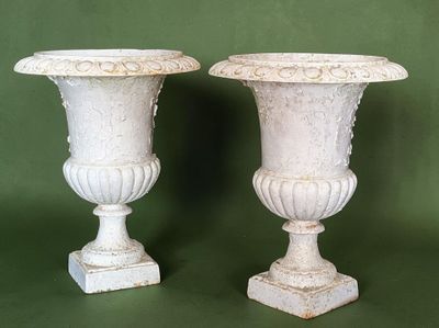 two white vases sitting next to each other on a green background