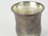 a small metal cup with a gold rim on a white surface