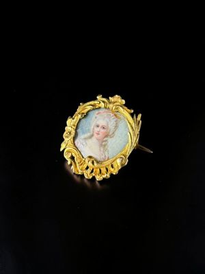 a gold plated broochle with a portrait of a woman