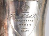 a silver vase sitting on a table in front of a white wall
