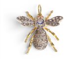 a gold and diamond bee broochle on a white background