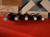 several bottles of wine are lined up on a red table cloth