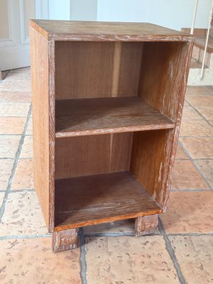 une petite bibliothèque en bois posée à même le sol dans une pièce