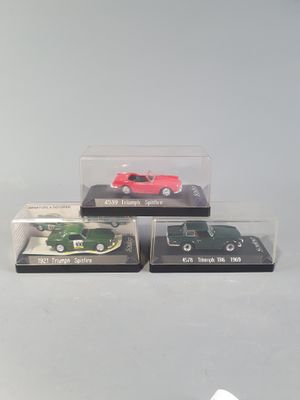 three miniature cars in a display case on a table