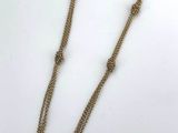 a gold necklace with a rectangular stone on a chain