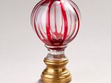 une boule en verre rayée de rouge et de blanc posée sur un socle doré