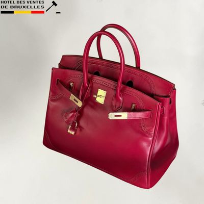 the red leather handbag is sitting on a white surface