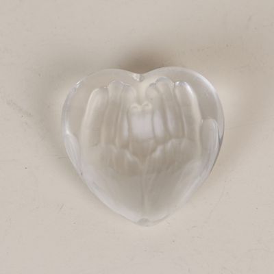 un objet en verre en forme de cœur posé sur une surface blanche
