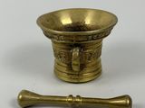 an old brass mortar and a wooden spoon on a white surface