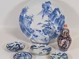 une assiette, des bols et un vase bleus et blancs posés sur une table