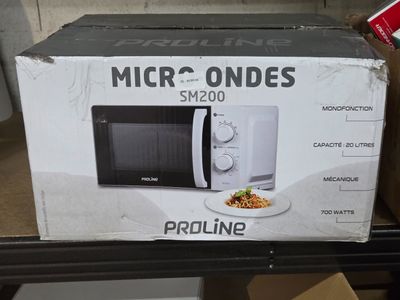 emballage d'un micro-ondes posé sur une table, avec une assiette de nourriture devant