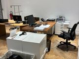 a room with a desk, a chair, a computer and a trash can in it