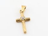 un pendentif en forme de croix en or orné d'un diamant sur fond blanc