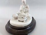 a white statue of a man sitting on a table