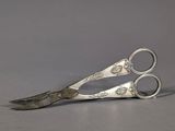 pair of silver scissors on a gray surface with a gray background