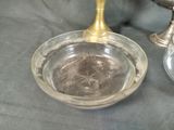 a glass bowl with a candle on a table next to a silver cup