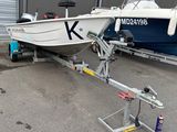 a white boat on a trailer parked in front of a building