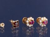 trois paires de boucles d'oreilles à clous en rubis et diamants posées sur une surface réfléchissante