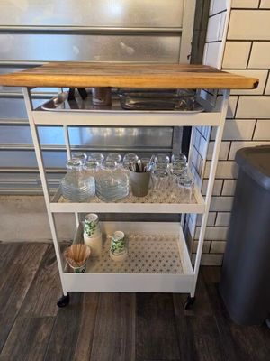 a kitchen cart with a cutting board on top of it