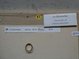 a gold ring with a smiley face on it next to a piece of paper