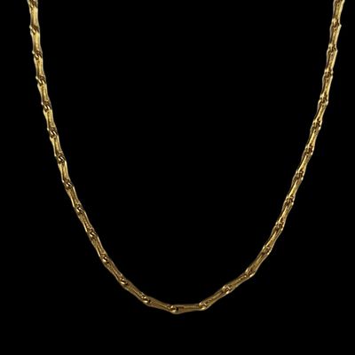 un collier en or avec une chaîne torsadée sur fond noir