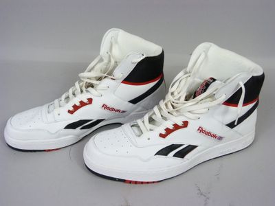 une paire de baskets blanches et noires avec des touches de rouge sur fond blanc
