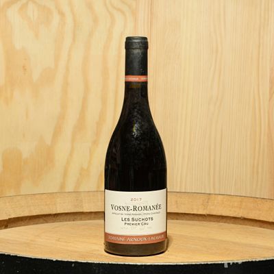 a bottle of wine sitting on top of a barrel