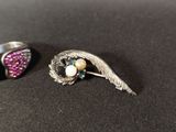 pair of silver and pink earrings with wings and pearls on a black surface