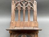 un vieux banc en bois dont le dossier présente un motif gothique