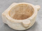 a stone bowl with a handle sitting on the floor