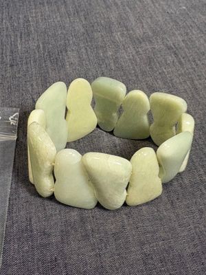 un bracelet composé de pierres vertes sur un fond gris