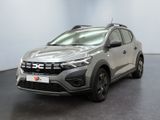 Une voiture argentée est garée dans une pièce au sol noir.