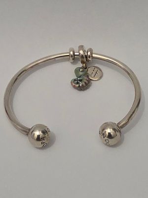 a close up of a silver bracelet with two charms on it