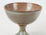 a brown and green bowl sitting on a white surface