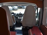 two seats in the back of a van with a red seat cover