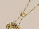 a close up of a gold necklace with pearls and flowers