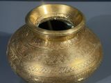a gold vase sitting on a table with a blue background