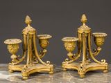 une paire de bougeoirs anciens en laiton posés sur une table en marbre, sur fond gris