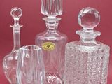 trois bouteilles en verre et un vase en verre sur un fond rose