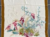 une photo d'un foulard carré à motifs floraux posé sur un sol carrelé