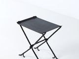 le petit tabouret pliant noir est posé sur une surface blanche