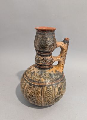 un vase muni d'une anse, posé sur une table