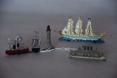 trois bateaux miniatures et un phare posés sur une table
