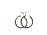 une paire de boucles d'oreilles créoles noires sur fond blanc