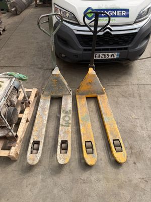 un chariot élévateur et deux palettes posées au sol