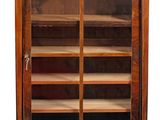 an antique wooden bookcase with glass doors and shelves on casteors