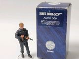 a figurine of a man holding a gun in front of a box of james bond 002 agent 006