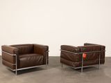 a pair of brown leather chairs in a room with a white wall