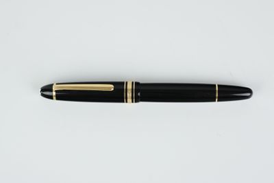 un stylo plume noir et doré posé sur une surface blanche